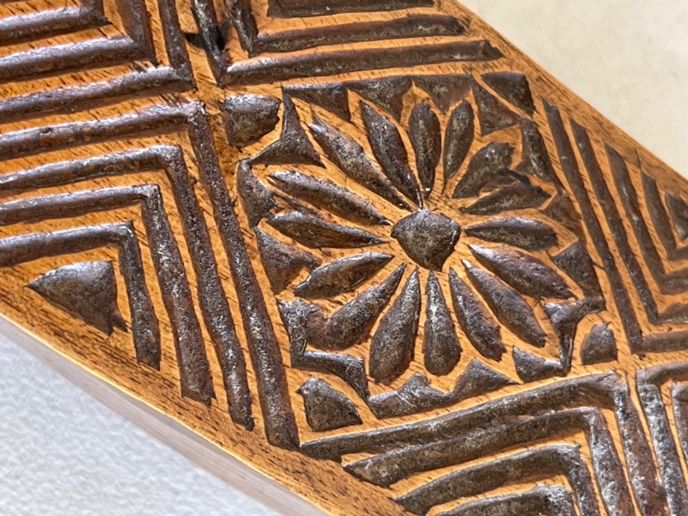 A narrow, elongated carved wooden press mould featuring repeating geometric diamond and rosette patterns in a warm brown finish. View II