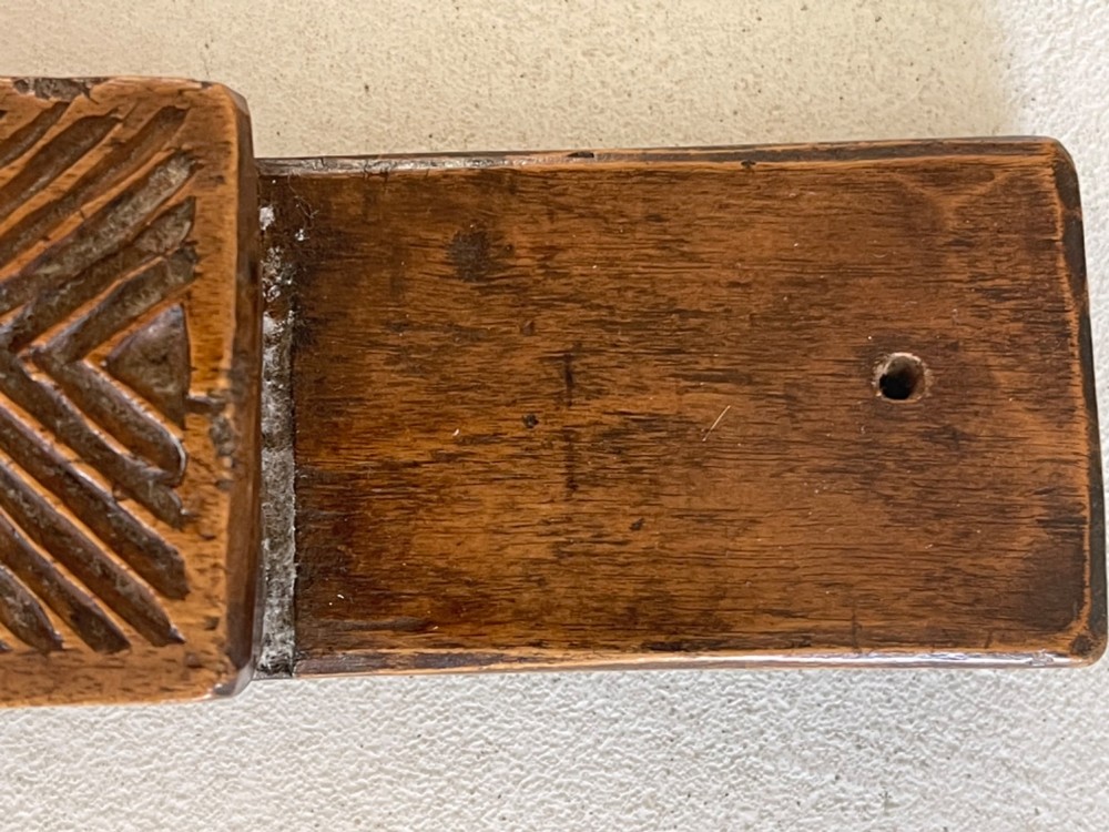 A narrow, elongated carved wooden press mould featuring repeating geometric diamond and rosette patterns in a warm brown finish. View III
