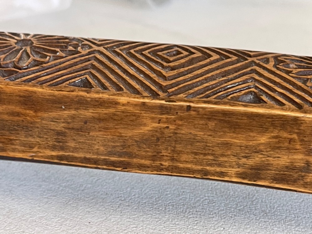 A narrow, elongated carved wooden press mould featuring repeating geometric diamond and rosette patterns in a warm brown finish. View IV