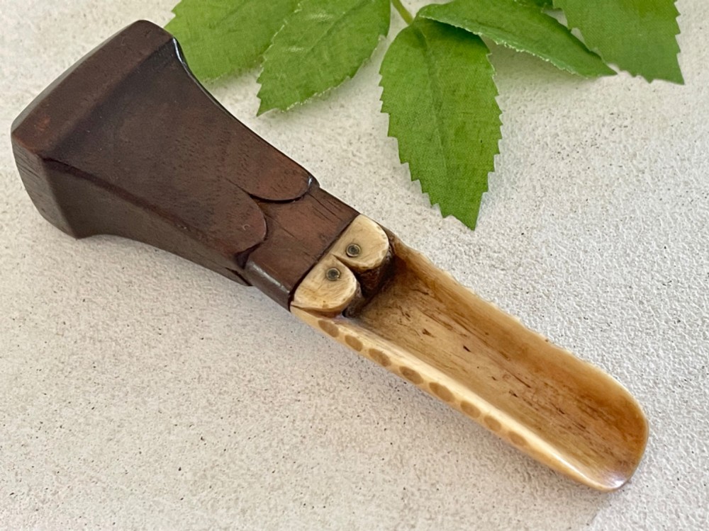 A Georgian treen apple corer featuring a dark mahogany handle joined to a carved bone scoop with metal pins.