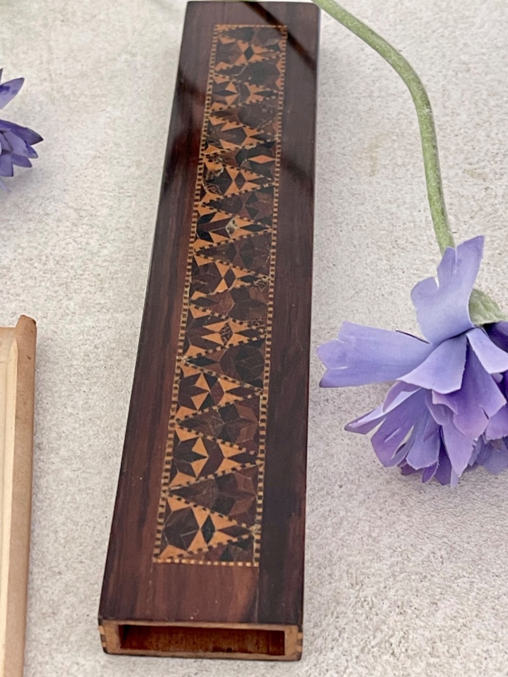 A long rectangular dark rosewood silk skein holder featuring a central band of intricate geometric tessellated wood inlay.