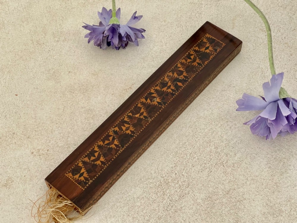 A long rectangular dark rosewood silk skein holder featuring a central band of intricate geometric tessellated wood inlay. View X