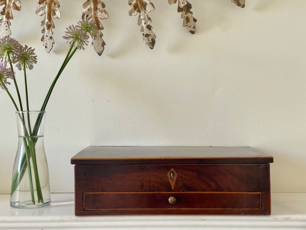 A rectangular Georgian flame mahogany jewellery box featuring a lower drawer, brass knob, and diamond inlay escutcheon.
