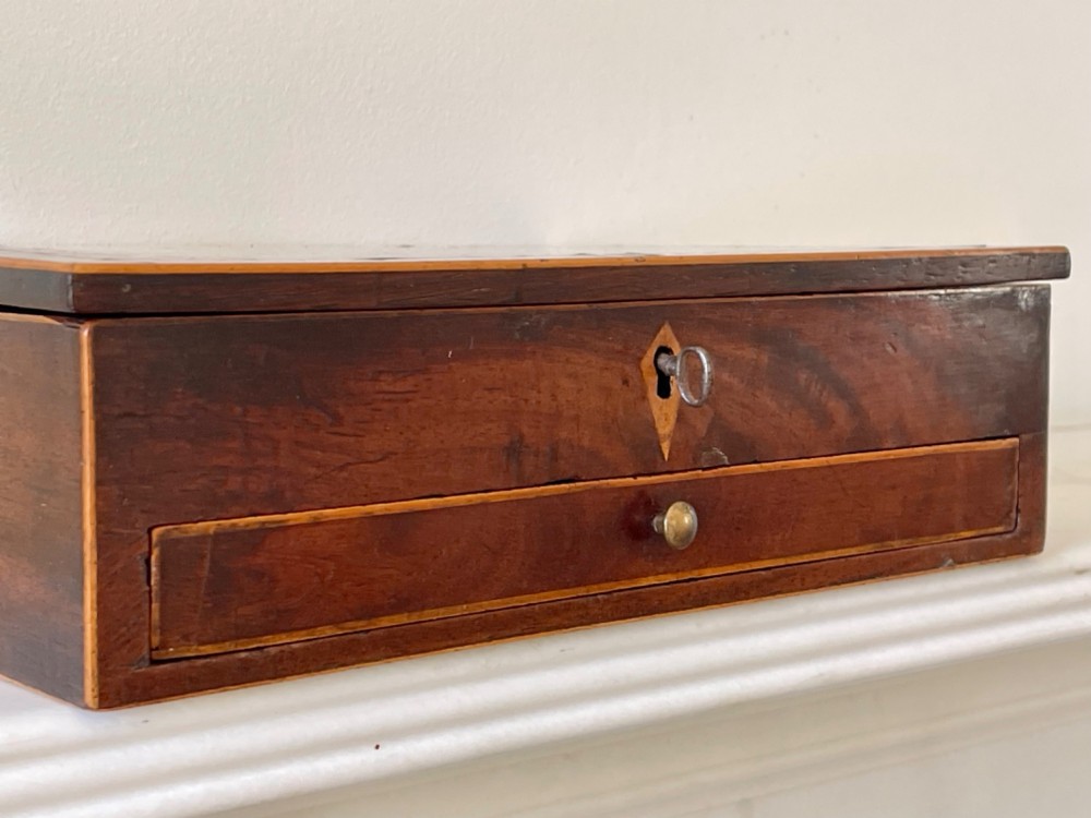 A rectangular Georgian flame mahogany jewellery box featuring a lower drawer, brass knob, and diamond inlay escutcheon. View II