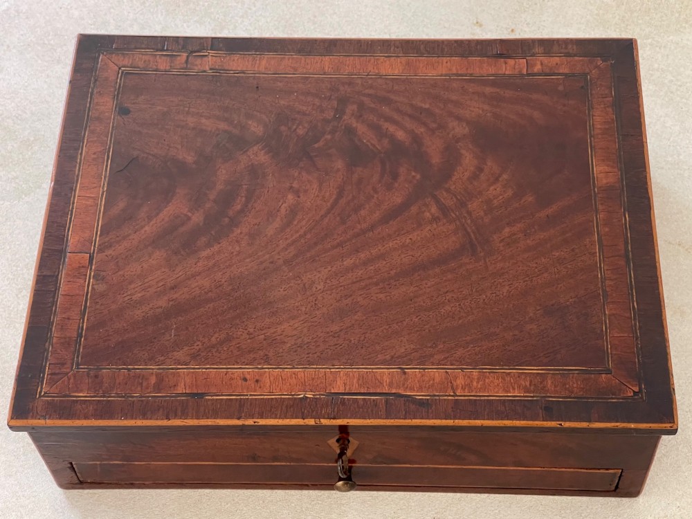 A rectangular Georgian flame mahogany jewellery box featuring a lower drawer, brass knob, and diamond inlay escutcheon. View IV