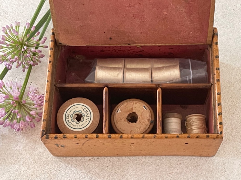 An antique Georgian wooden reel box painted in warm ochre with a floral motif on the lid and thread apertures along the front. View II
