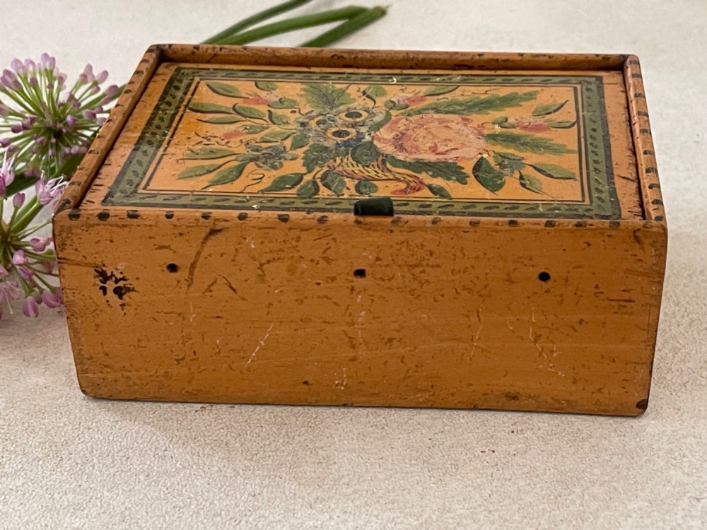 An antique Georgian wooden reel box painted in warm ochre with a floral motif on the lid and thread apertures along the front. View V