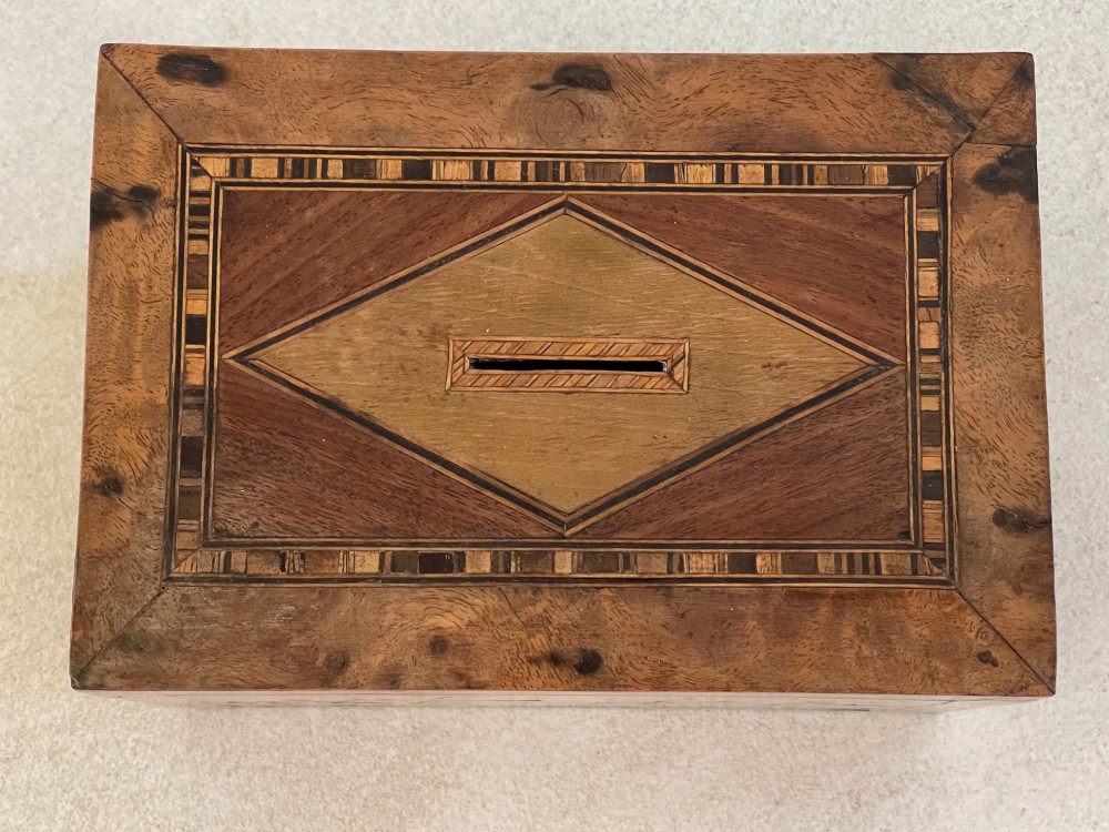 A rectangular mahogany money box featuring an inlaid wooden marquetry panel depicting a steamship at sea alongside a lighthouse. View V