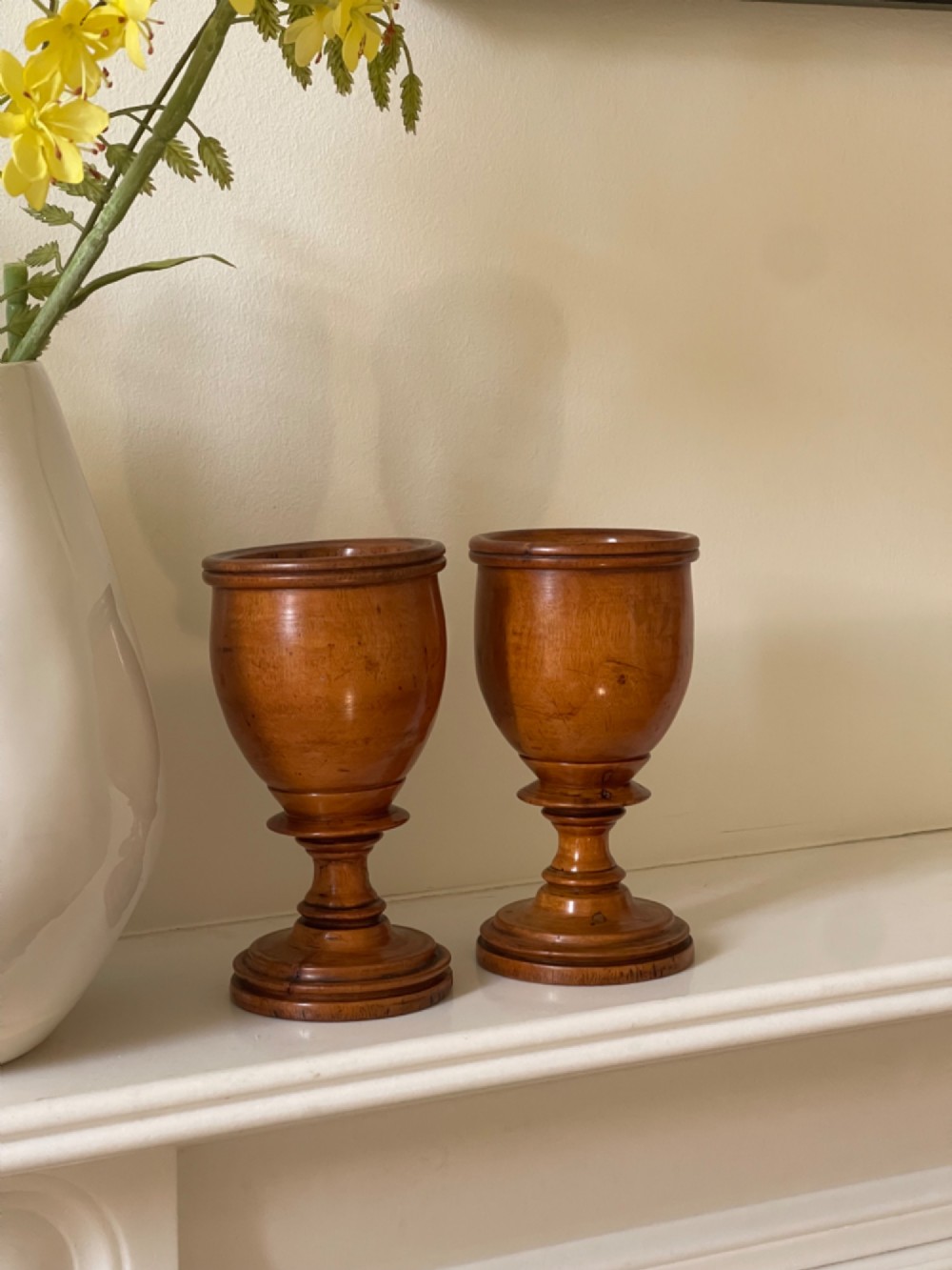 A pair of turned fruitwood goblets featuring knopped stems and stepped circular bases set against a plain background. View V