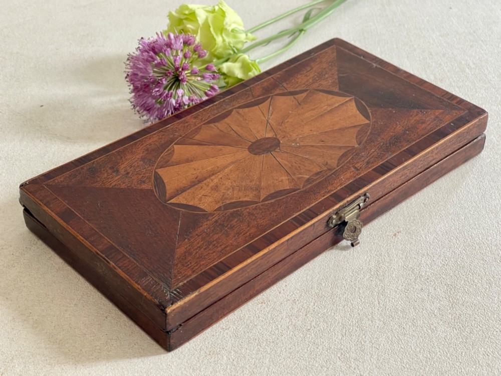 A rectangular Georgian folding wooden games board featuring central oval shell marquetry inlay, crossbanded borders, and a brass latch on the side.