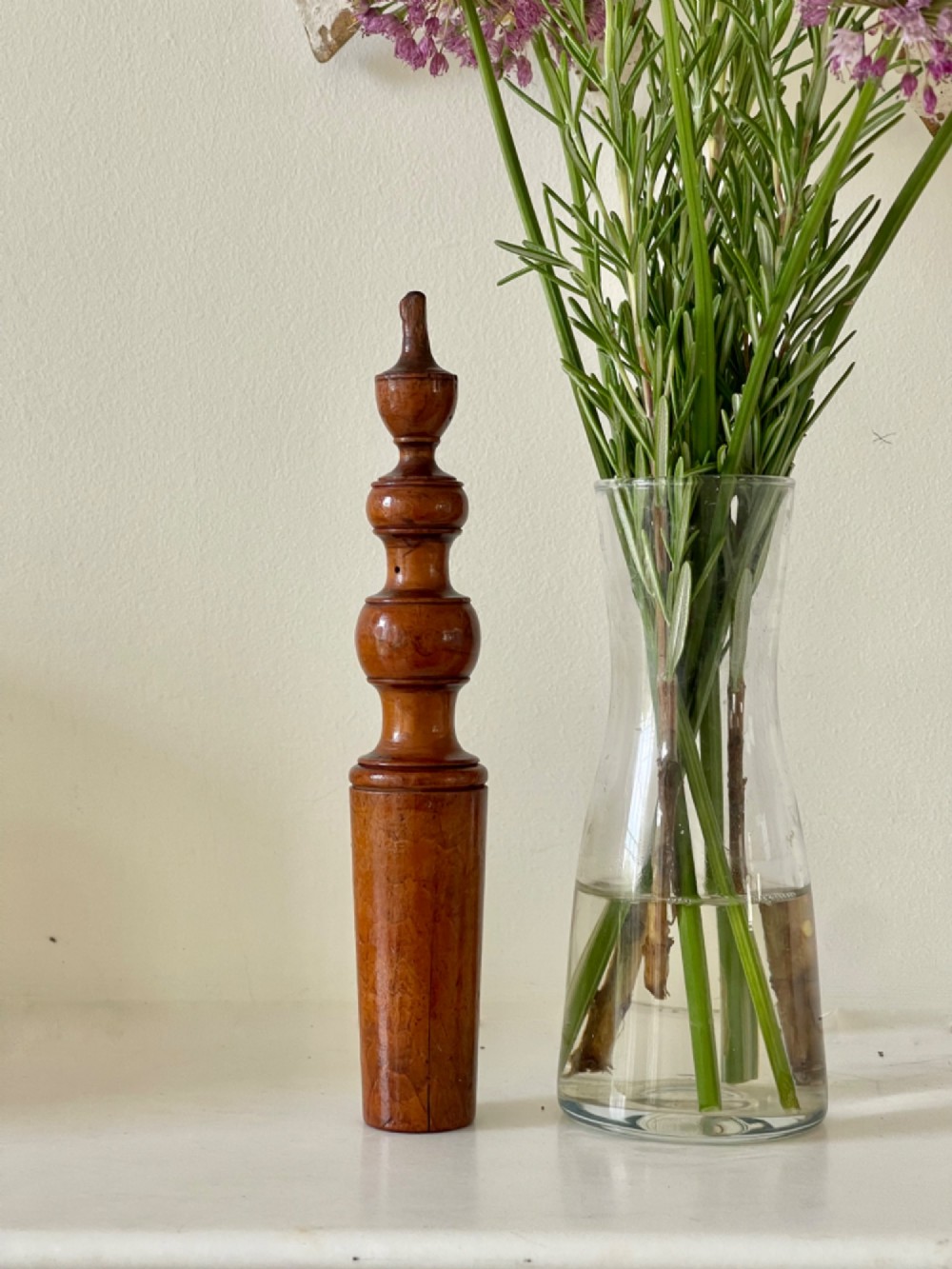 A hand-turned antique wooden childs rattle featuring turned baluster detailing and a tapered cylindrical base with a warm polished finish.
