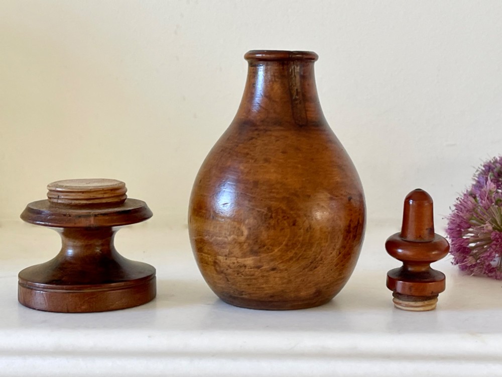 A turned brown hardwood spice flask featuring a bulbous body, finial stopper, and a stepped circular pedestal base. View III