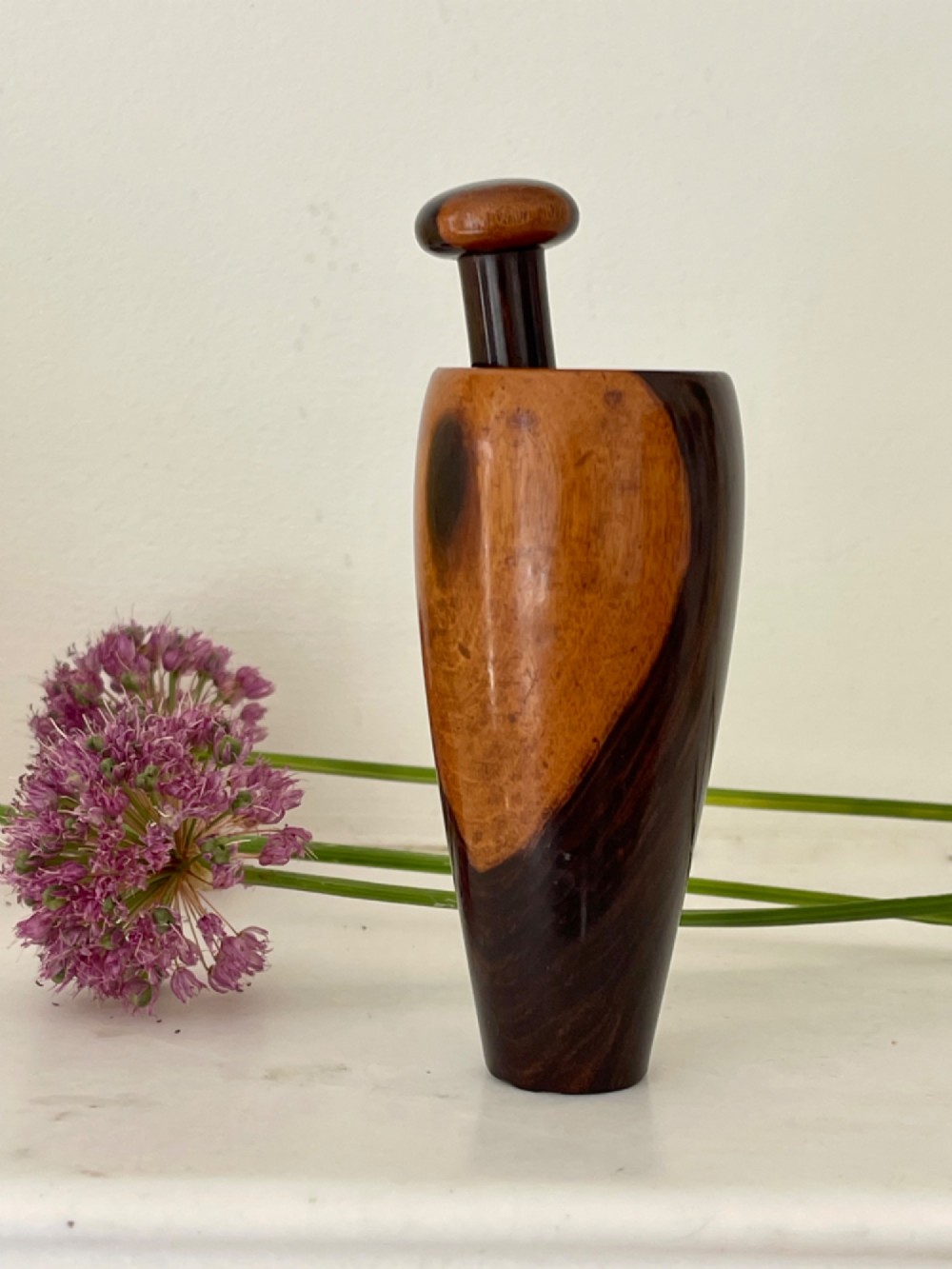 A hand-turned wooden snuff mortar and pestle crafted from contrasting dark and light grain hardwood. View II