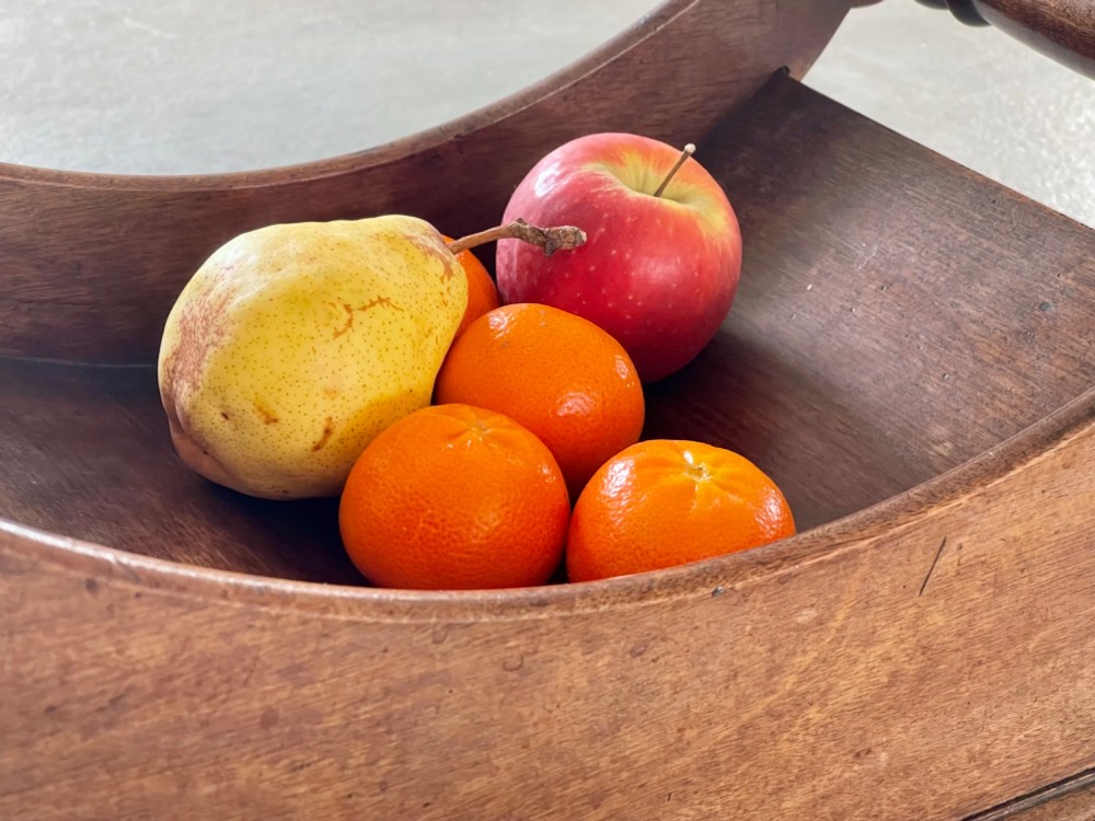 A curved Georgian mahogany cheese coaster with turned end handles and small brass castors on the base. View V
