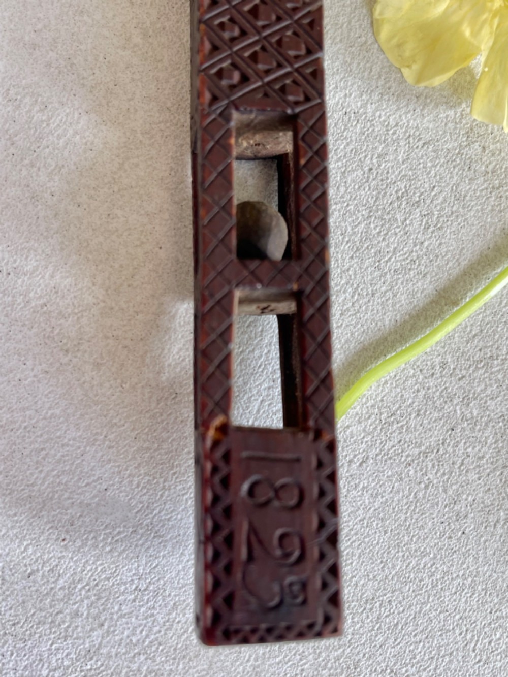 A dark hand-carved wooden treen knitting sheath featuring geometric chip carving, a ball-in-cage detail, and a carved heart motif. View II