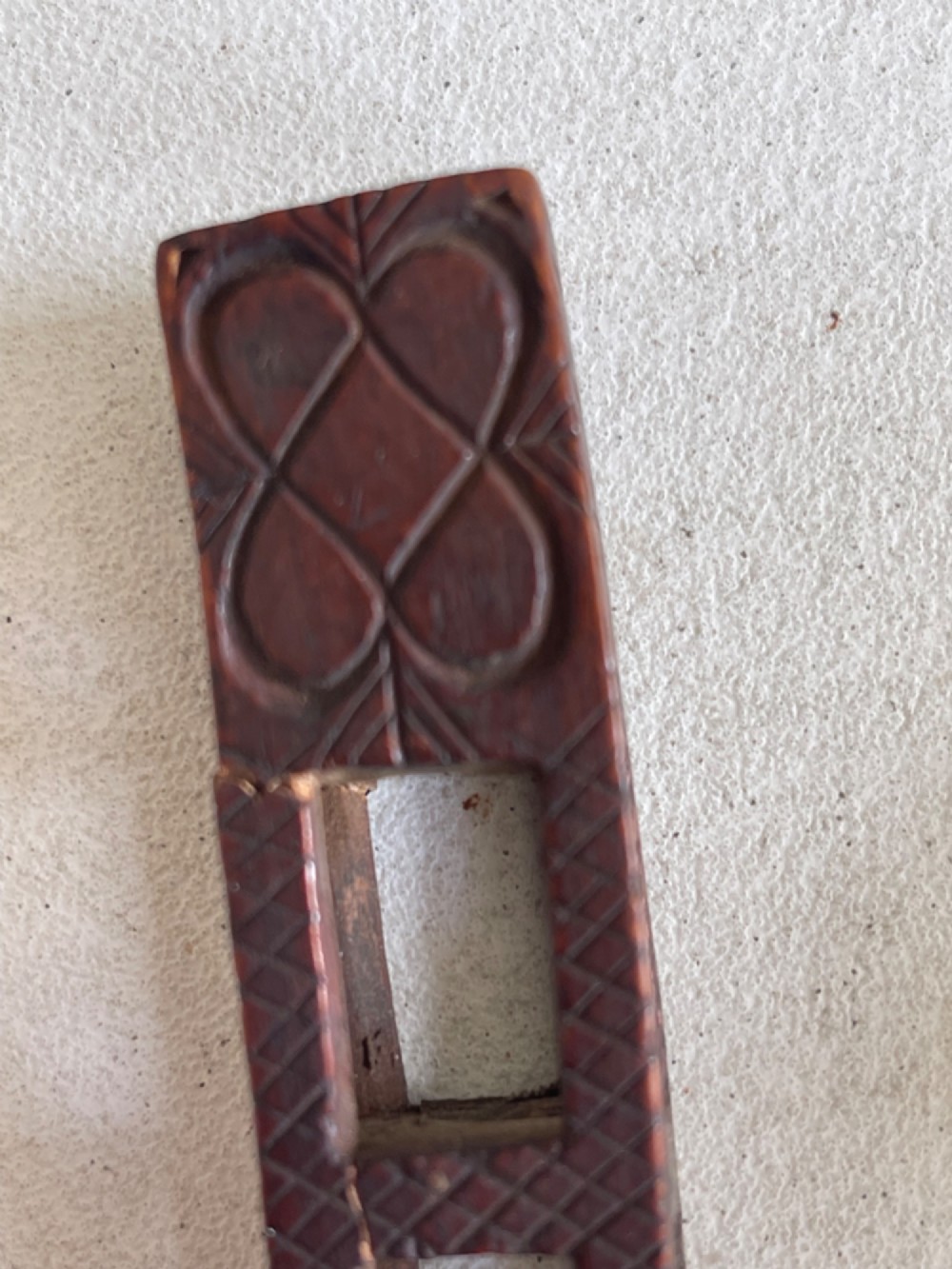 A dark hand-carved wooden treen knitting sheath featuring geometric chip carving, a ball-in-cage detail, and a carved heart motif. View III