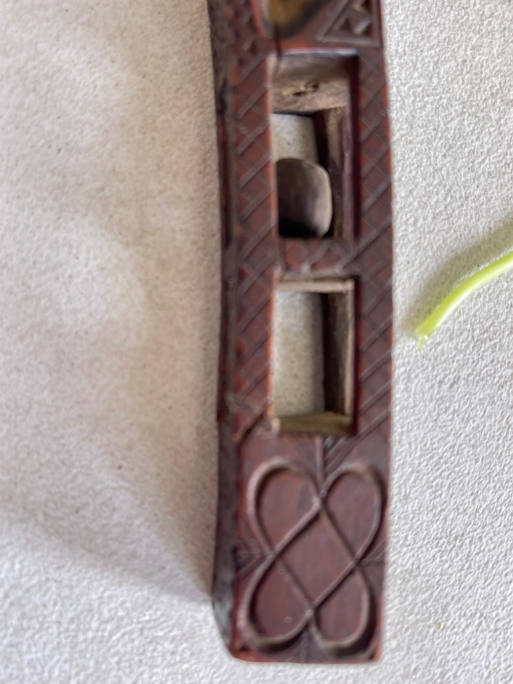 A dark hand-carved wooden treen knitting sheath featuring geometric chip carving, a ball-in-cage detail, and a carved heart motif. View VIII