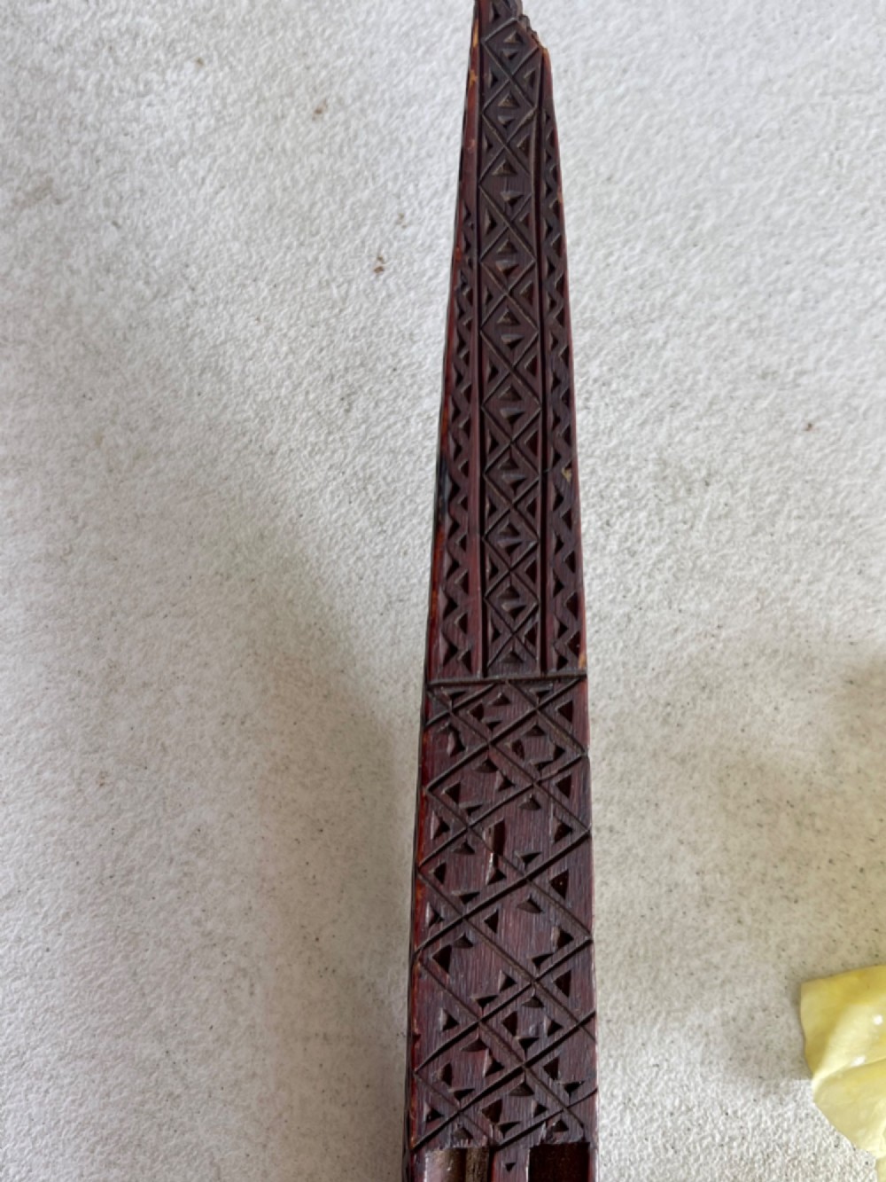 A dark hand-carved wooden treen knitting sheath featuring geometric chip carving, a ball-in-cage detail, and a carved heart motif. View IX