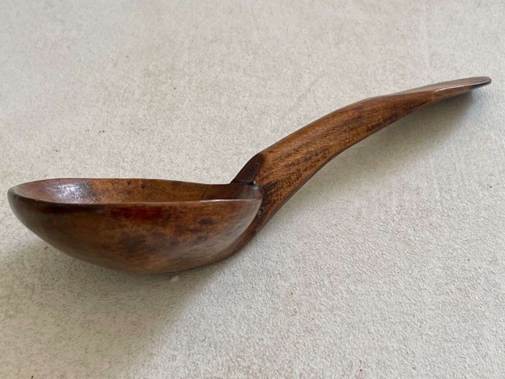 A hand-carved antique treen wooden ladle featuring a deep circular bowl and a shaped handle with decorative notched detailing. View IV
