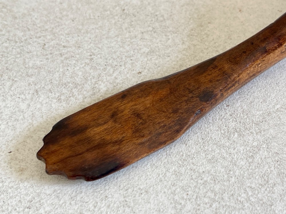 A hand-carved antique treen wooden ladle featuring a deep circular bowl and a shaped handle with decorative notched detailing. View VI