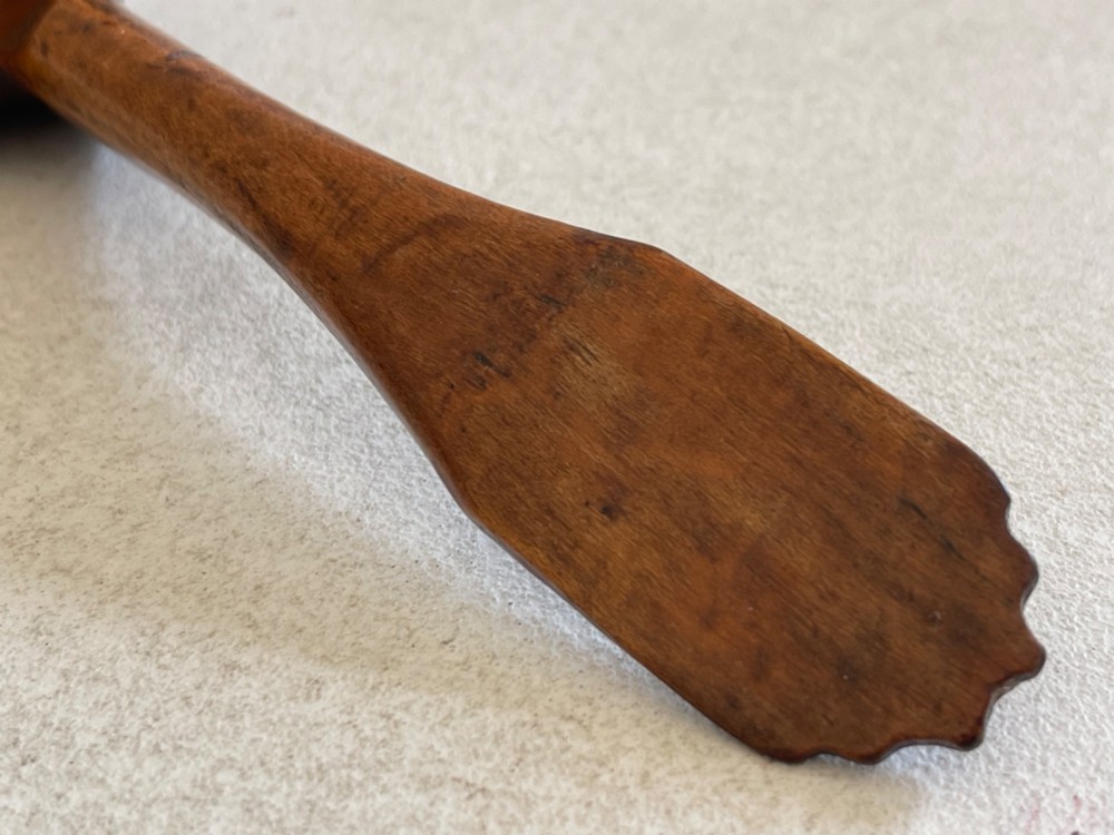 A hand-carved antique treen wooden ladle featuring a deep circular bowl and a shaped handle with decorative notched detailing. View VII