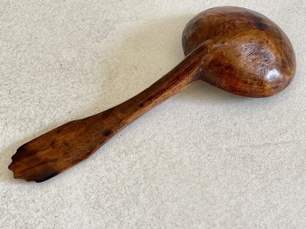 A hand-carved antique treen wooden ladle featuring a deep circular bowl and a shaped handle with decorative notched detailing. View VIII