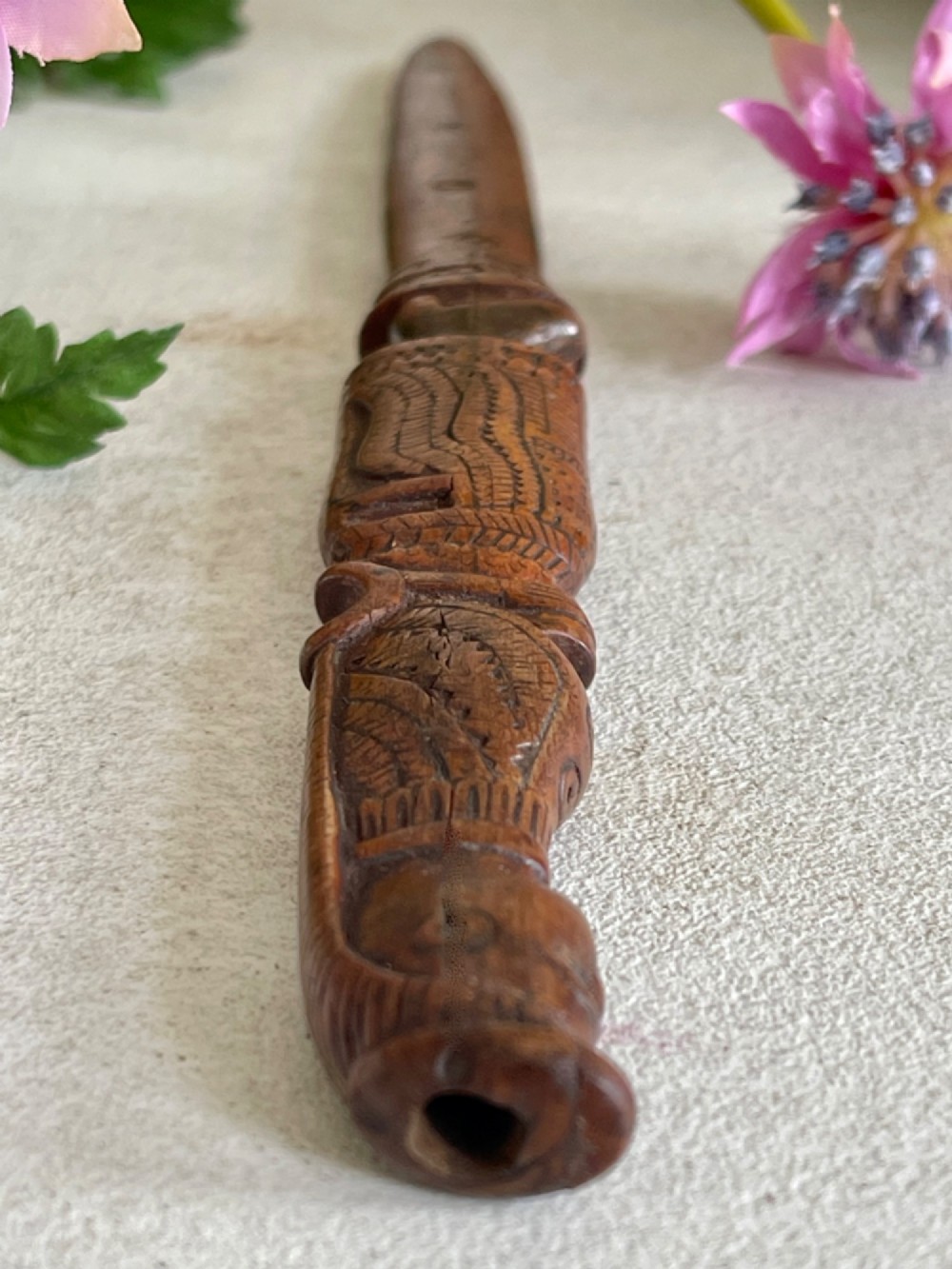 A hand-carved brown wooden knitting sheath decorated with a figurative bird motif at the top and incised geometric circles along the body. View II