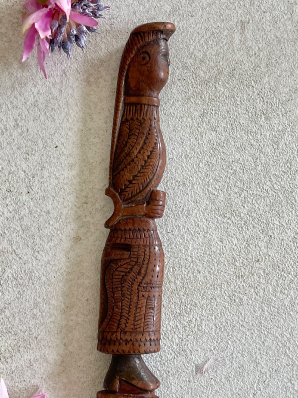 A hand-carved brown wooden knitting sheath decorated with a figurative bird motif at the top and incised geometric circles along the body. View III