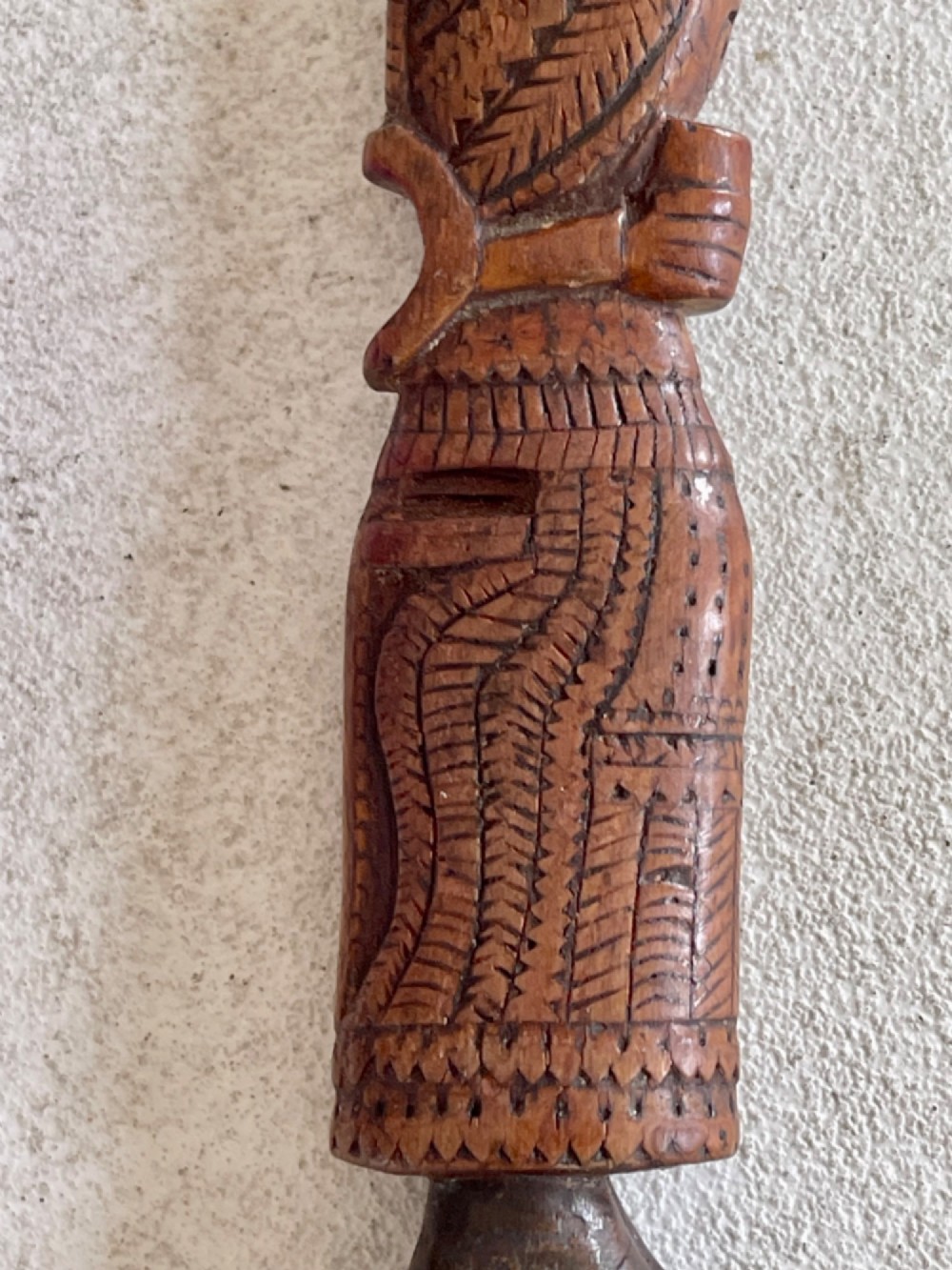 A hand-carved brown wooden knitting sheath decorated with a figurative bird motif at the top and incised geometric circles along the body. View IV