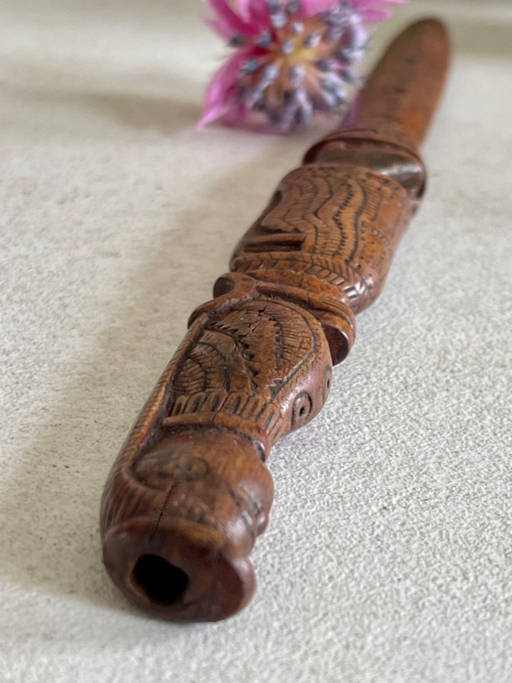 A hand-carved brown wooden knitting sheath decorated with a figurative bird motif at the top and incised geometric circles along the body. View V