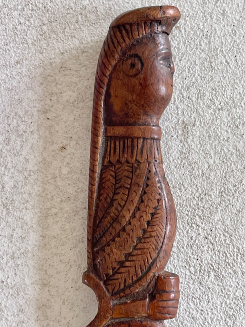 A hand-carved brown wooden knitting sheath decorated with a figurative bird motif at the top and incised geometric circles along the body. View VII
