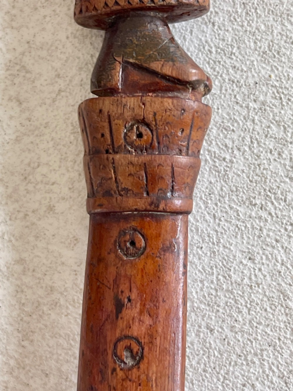A hand-carved brown wooden knitting sheath decorated with a figurative bird motif at the top and incised geometric circles along the body. View VIII