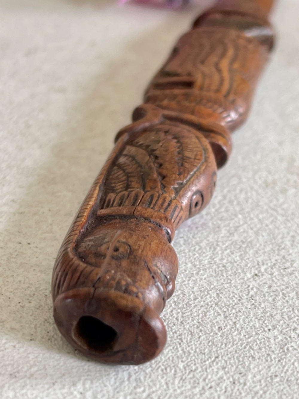 A hand-carved brown wooden knitting sheath decorated with a figurative bird motif at the top and incised geometric circles along the body. View IX