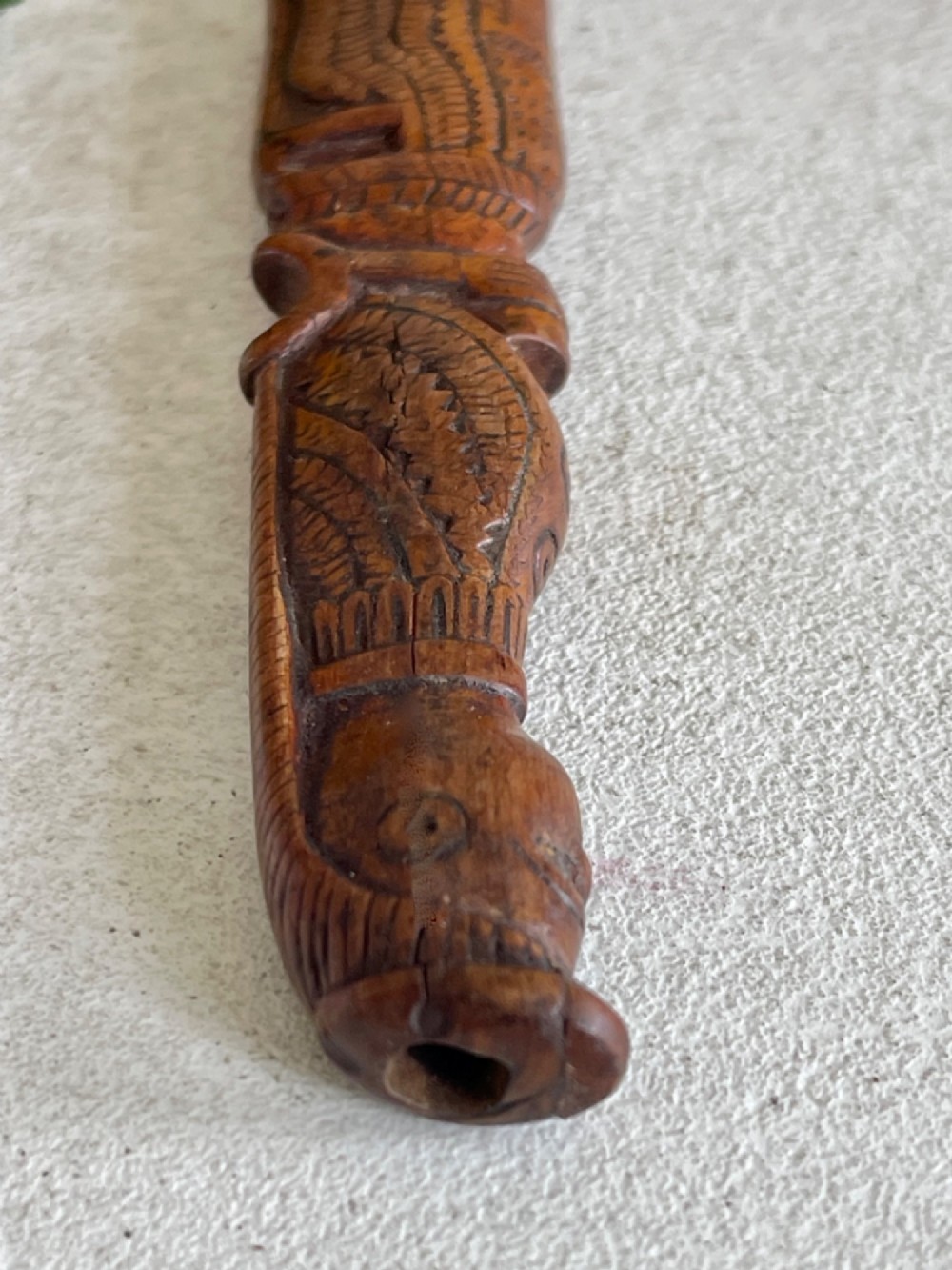 A hand-carved brown wooden knitting sheath decorated with a figurative bird motif at the top and incised geometric circles along the body. View X