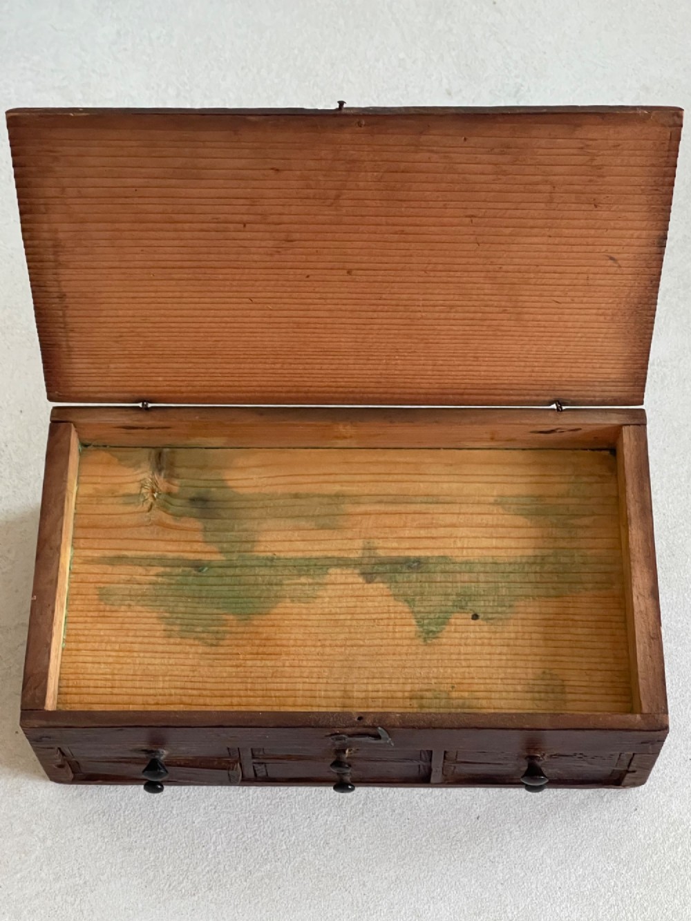 A dark pine antique watchmakers box featuring a hinged top lid, metal clasp, and six small wooden drawers with turned knobs. View VI