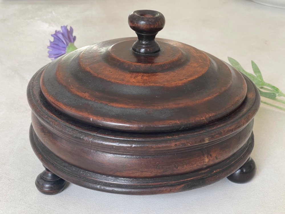 A dark turned wood circular tabletop roulette game featuring a stepped fitted lid with a turned central finial raised on bun feet. View III