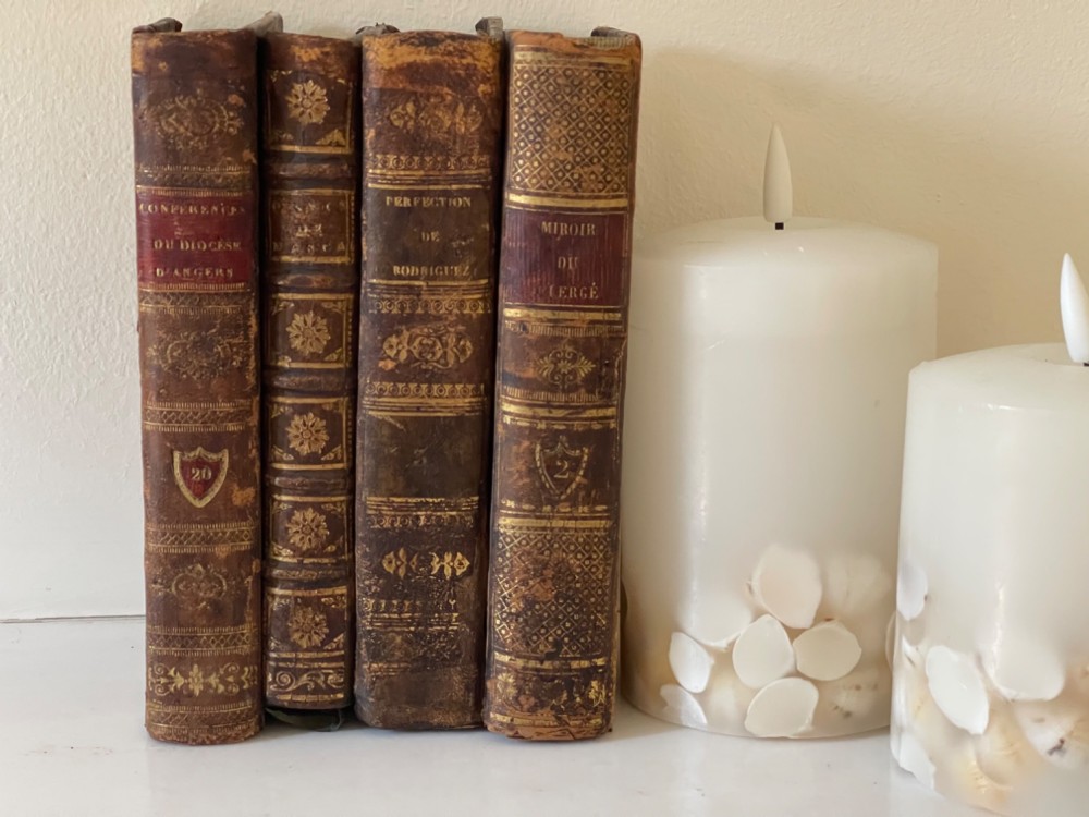 An antique novelty box crafted to resemble four French leather-bound book spines with gilt detailing and embossed text.
