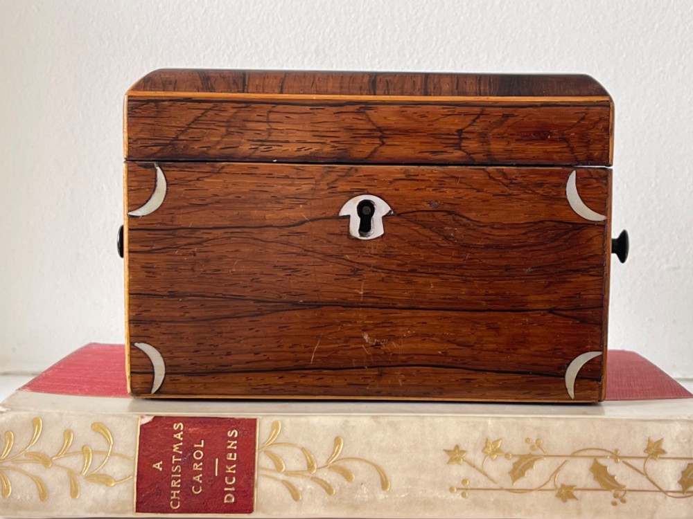 An antique rectangular rosewood box featuring a hinged lid, mother-of-pearl crescent corner inlays, and a central brass keyhole escutcheon.
