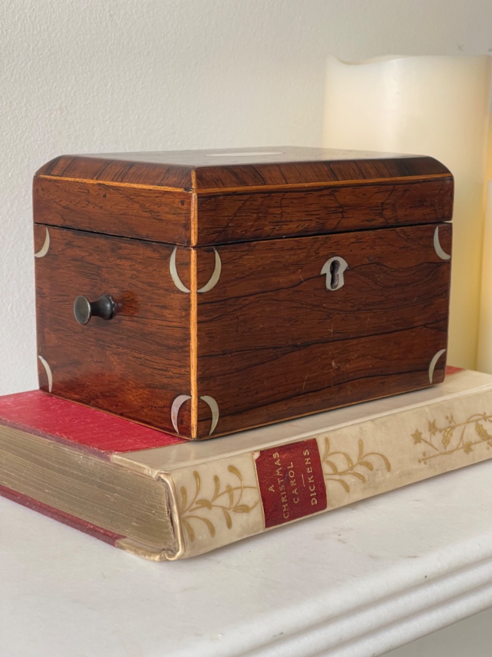 An antique rectangular rosewood box featuring a hinged lid, mother-of-pearl crescent corner inlays, and a central brass keyhole escutcheon. View II