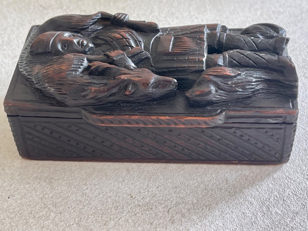 A dark carved wooden table snuff box lid depicting a Scottish Highlander in a kilt carrying a stag across his shoulders with a hound at his feet. View III