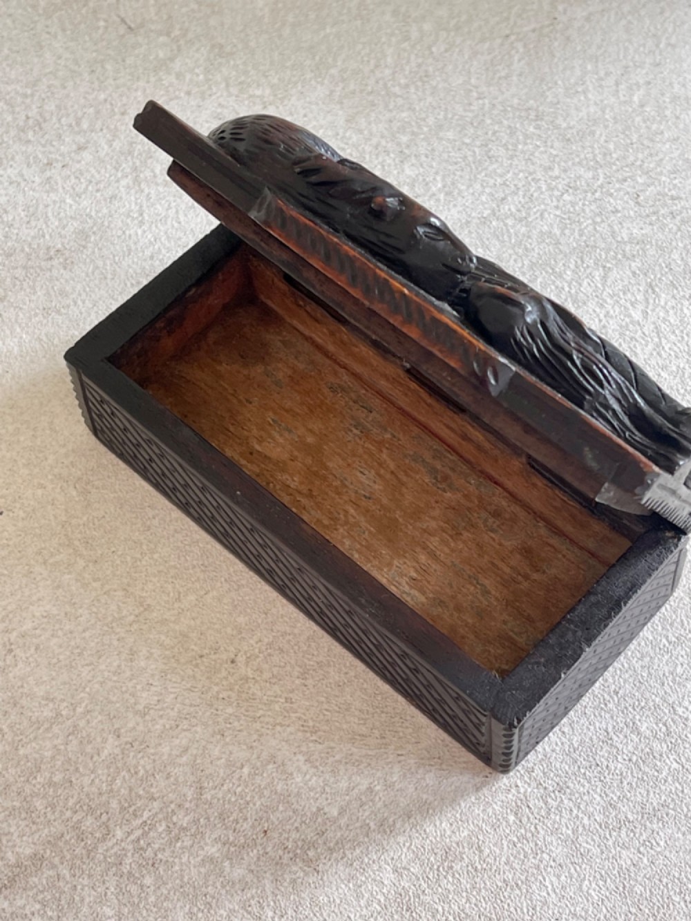 A dark carved wooden table snuff box lid depicting a Scottish Highlander in a kilt carrying a stag across his shoulders with a hound at his feet. View VI