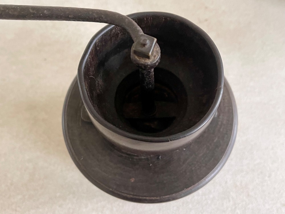 A turned dark brown lignum vitae coffee grinder with a curved iron crank handle and turned wooden knob. View III
