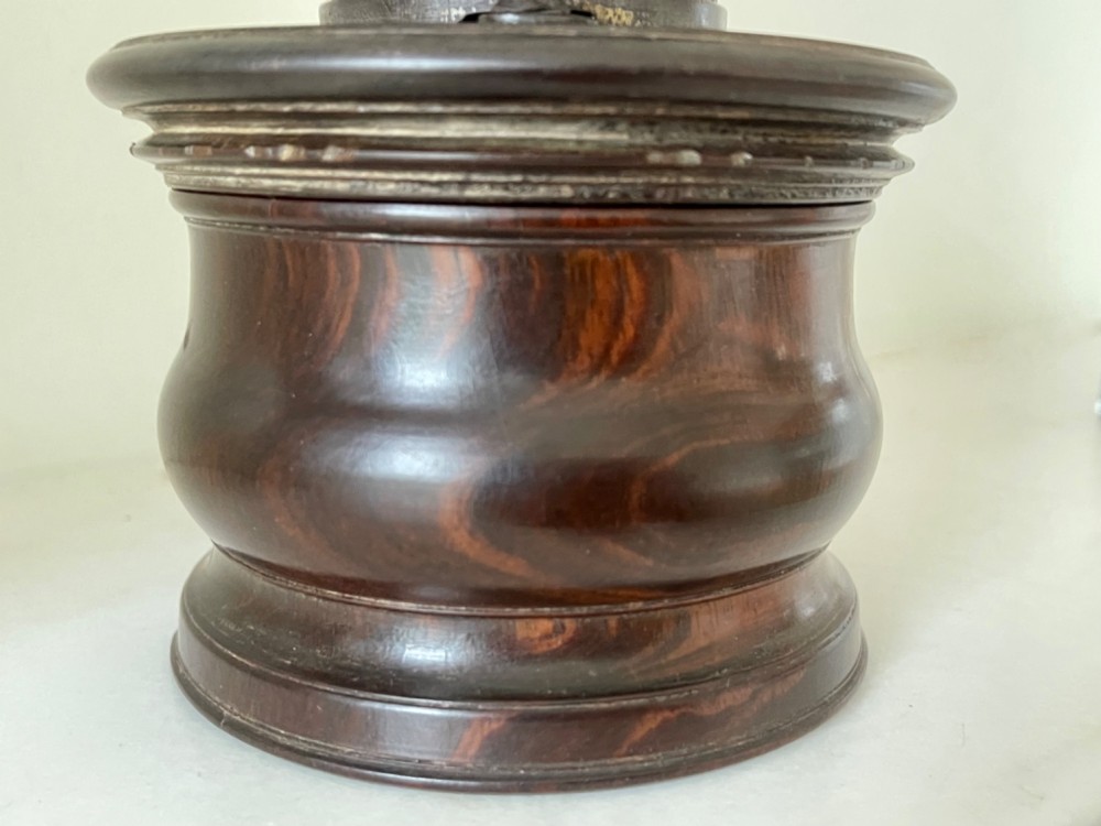 A turned dark brown lignum vitae coffee grinder with a curved iron crank handle and turned wooden knob. View IV