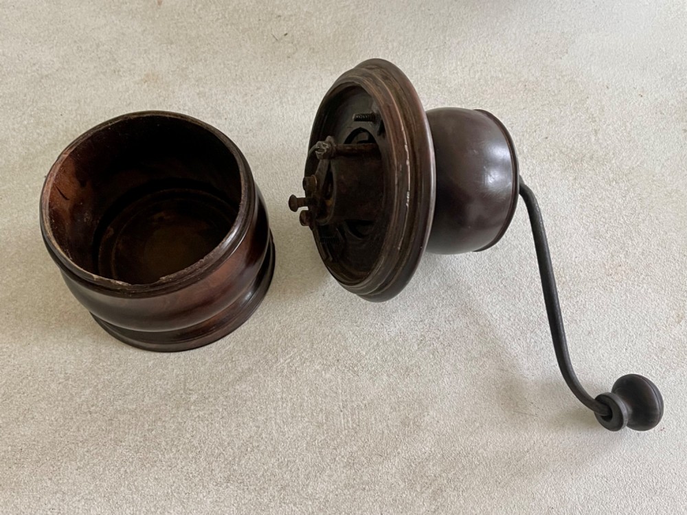 A turned dark brown lignum vitae coffee grinder with a curved iron crank handle and turned wooden knob. View V