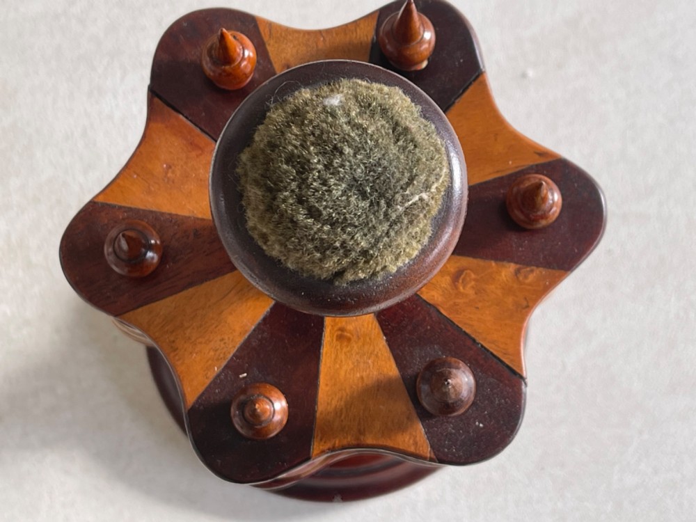 A turned dark mahogany cotton reel stand featuring a central pillar topped with a green fabric pin cushion and surrounded by brass spindles holding wooden thread spools. View II