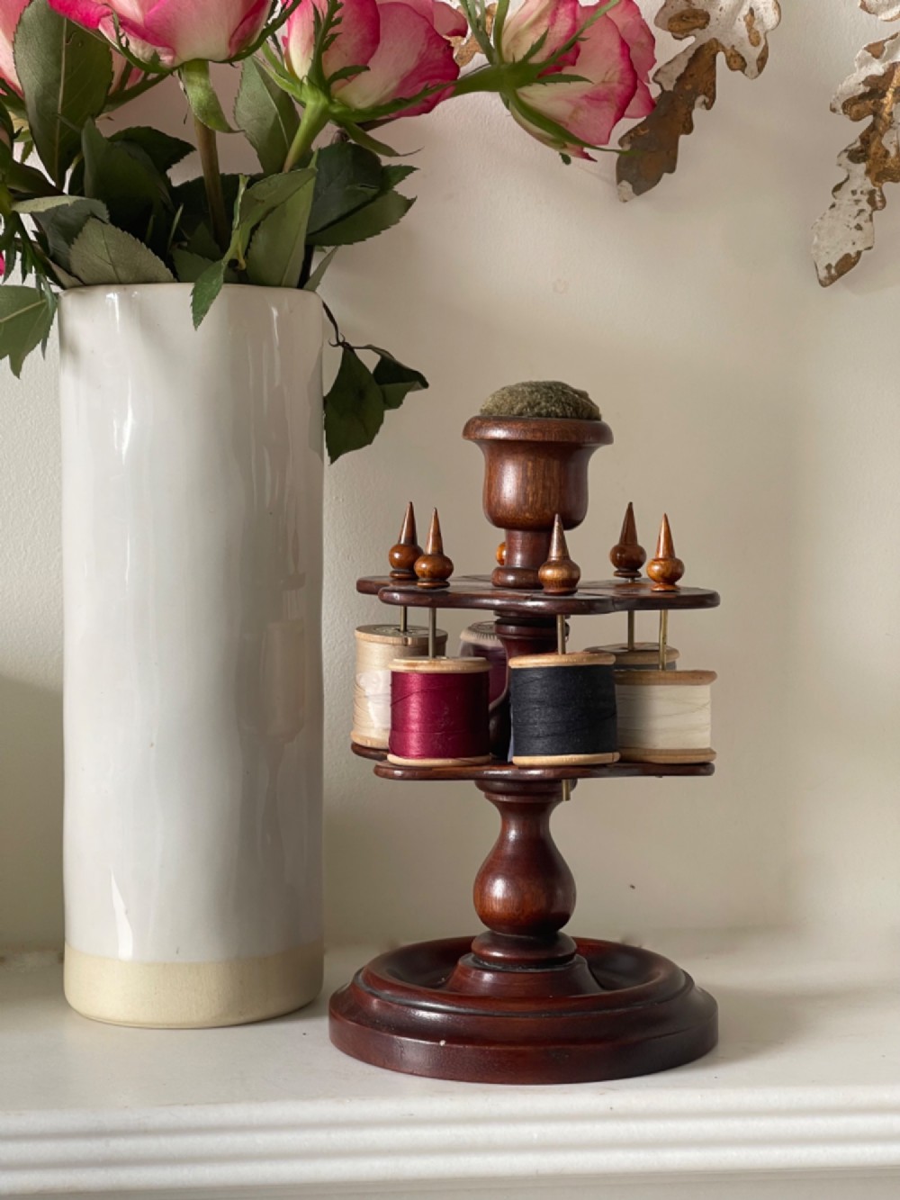A turned dark mahogany cotton reel stand featuring a central pillar topped with a green fabric pin cushion and surrounded by brass spindles holding wooden thread spools. View III