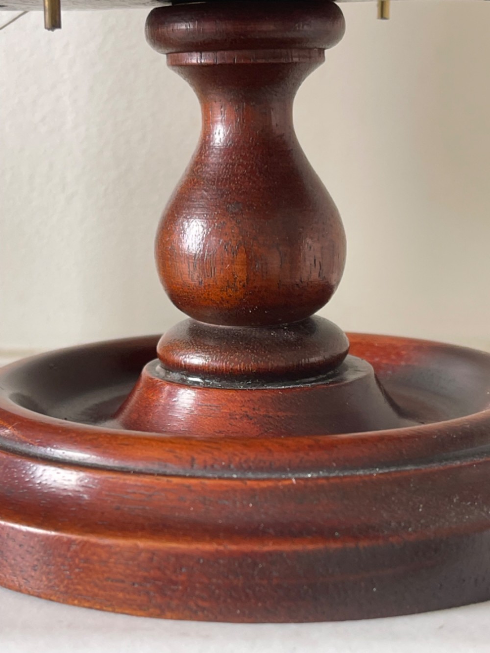 A turned dark mahogany cotton reel stand featuring a central pillar topped with a green fabric pin cushion and surrounded by brass spindles holding wooden thread spools. View IV