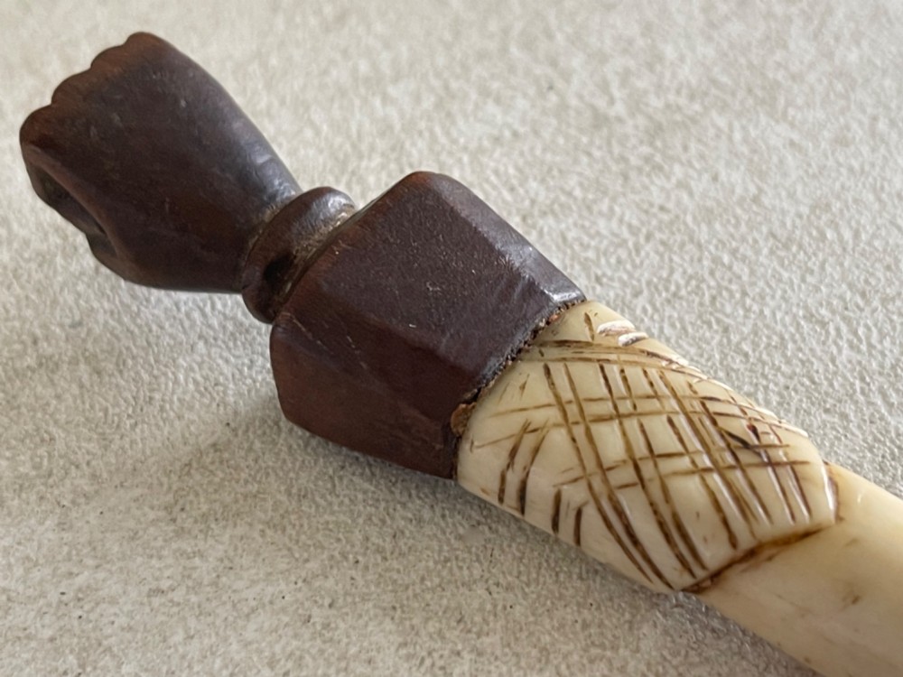 A carved antique bone and wooden apple scoop featuring a terminal in the shape of a clenched fist and carved lettering on the collar. View II