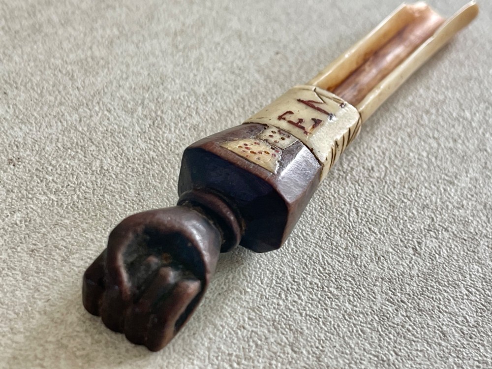A carved antique bone and wooden apple scoop featuring a terminal in the shape of a clenched fist and carved lettering on the collar. View III