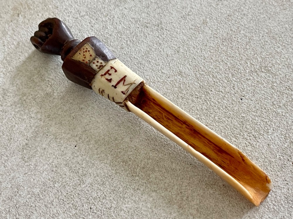A carved antique bone and wooden apple scoop featuring a terminal in the shape of a clenched fist and carved lettering on the collar. View V